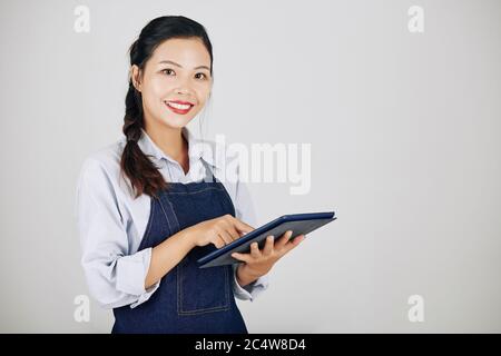 Portrait of young female coffeeshop owner using application on tablet computer when accepting orders from customers Stock Photo
