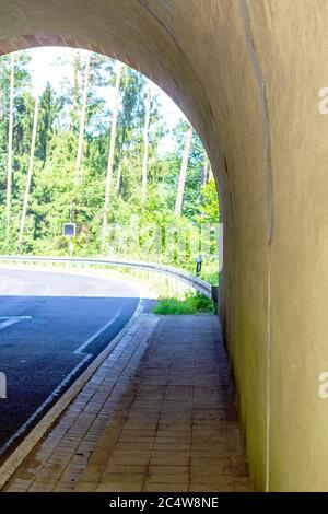 view through a railway tunnel, with focus on the gutter along the road Stock Photo