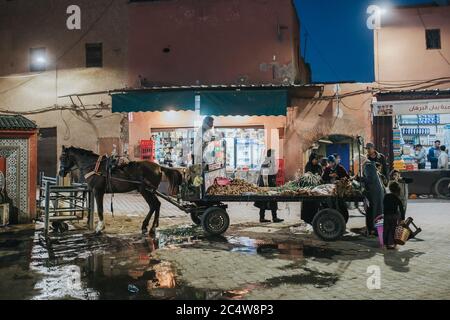 Marrakech, Morocco - March 11, 2019: People trading vegetables from a horse cart in Marrakech Medina, morocco. Stock Photo