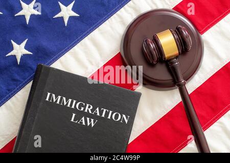 Immigration law text on black book and judge gavel on US of America flag background, top view. Migration, emigration visa in USA concept Stock Photo