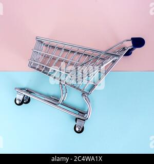 empty shopping cart over colour background, mini metal cart isolated on color background Stock Photo