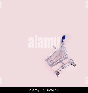 empty shopping cart over pink background, mini metal cart isolated on color background Stock Photo