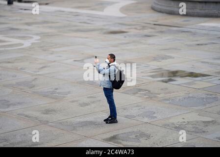 London, England, UK. Man wearing a facemask taking a photo in Trafalgar Square at the beginning of the Coronavirus crisis, March 2020 Stock Photo