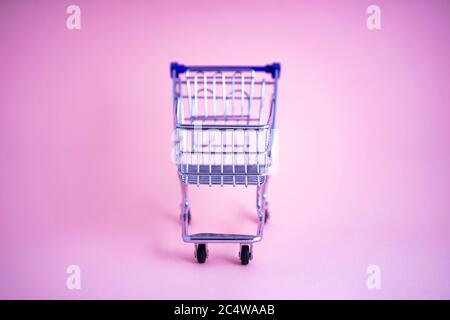 empty shopping cart over colour background, mini metal cart isolated on color background Stock Photo