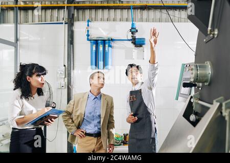 Inspectors checking modern coffee roastery production facility and asking owner about wiring Stock Photo