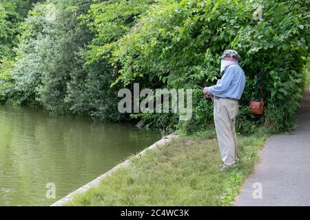 An older man wearing a bandana fishes in Kissena Lake in Kissena Park, Flushing, Queens, New York. Stock Photo