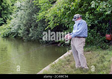 An older man wearing a bandana fishes in Kissena Lake in Kissena Park, Flushing, Queens, New York. Stock Photo