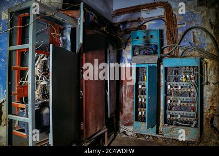Broken electrical switchgear cabinets with control panels in abandoned building Stock Photo