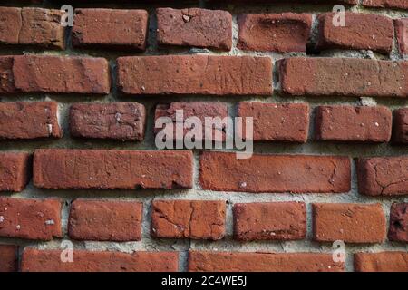 The wall is made of old hand-made cracked bricks. Stock Photo