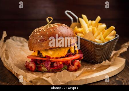 Bacon cheeseburger with french fries on wooden board Stock Photo
