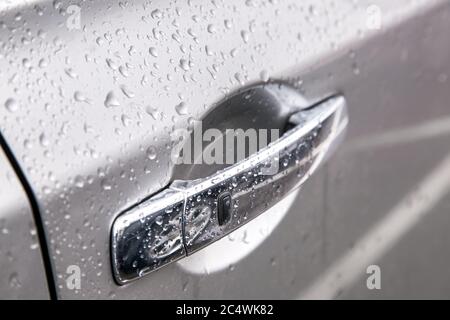 Car  chrome door handle with remote keyless opening button cover the water droplets after the rain, side view sharpness on the black button. Stock Photo