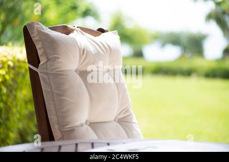 White wooden comfortable chair and a wooden table on a porch with garden view in summertime Stock Photo