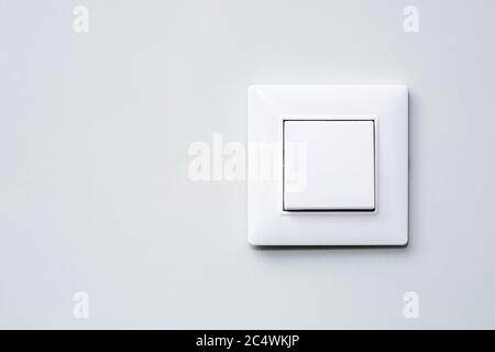 a light switch, a plastic mechanical switch of white color installed on a light gray wall. Stock Photo
