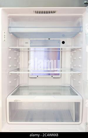 Refrigerator with empty shelves, food refrigerator in white with glass shelves and a tray for vegetables. Stock Photo