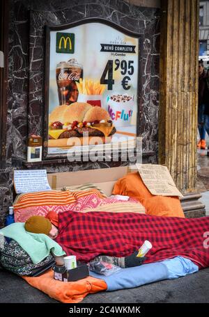 A homeless man sleeping rough outside a Mcdonalds restaurant, on the corner of the Calle de la Montera and the Gran Via, Madrid, Spain. Stock Photo