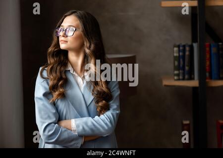 Portrait of amazing young business woman in blue glasses in the office. Stock Photo