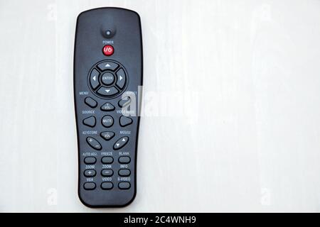 The remote control of the projector lies on a wooden table top view, close-up of the device with copy space for text. Stock Photo