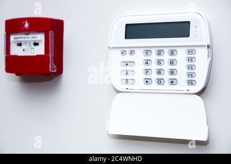 alarm control panel and fire button on a light gray wall, close-up of the security password entry system to activate and set the alarm. Stock Photo