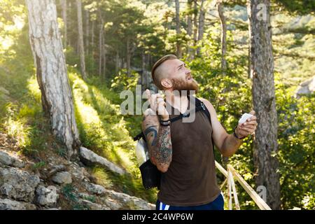 Bearded stylish hiker man using gps navigation for positioning at the mountain trail and thinks where to go. Technology concept Stock Photo