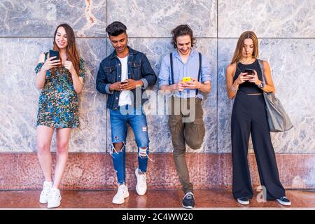 group of multiracial friends in front of a wall using smartphones to share content on social networks Stock Photo