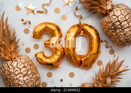 30th birthday celebration card with gold foil balloons and golden pineapples Stock Photo