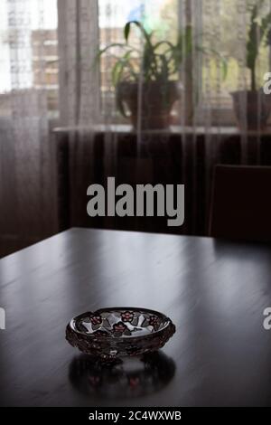 A dark room on the table is an empty ashtray Stock Photo