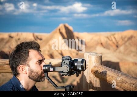 young filmmaker filming natural landscape in canyon with a large river and marshes Stock Photo