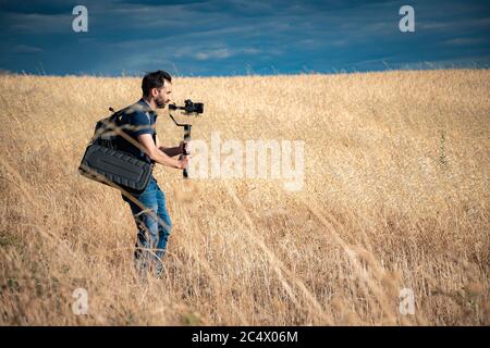 young filmmaker filming natural landscape in canyon with a large river and marshes Stock Photo