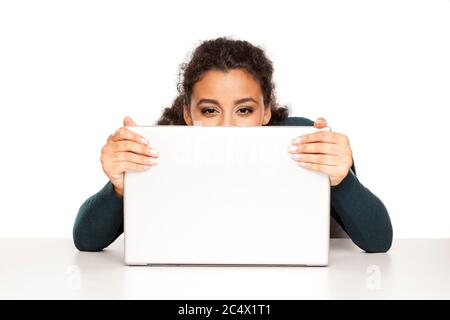 Beautiful happy african women peek behind her laptop on white background Stock Photo