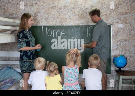 Parents teach their children at the blackboard in their home. Home school. Stock Photo