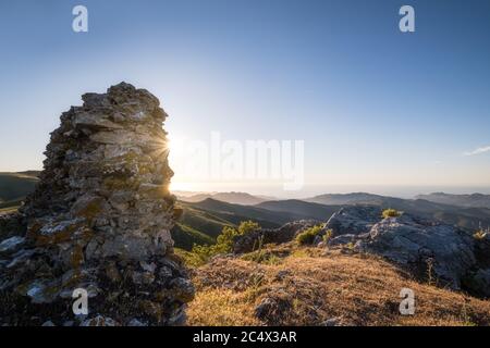 Sun setting behind an old stone wall looking over the north west coast of Corsica and the Mediterranean sea Stock Photo