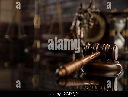 Law theme. Court library.  Gavel, scale and Themis statue on brown shining table. Collection of legal books in the bookshelf. Stock Photo