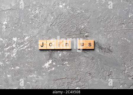 Join us word written on wood block. Join us text on cement table for your desing, Top view concept. Stock Photo