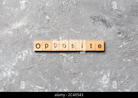 Opposite word written on wood block. Opposite text on cement table for your desing, concept. Stock Photo