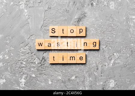 Stop wasting time word written on wood block. Stop wasting time text on cement table for your desing, Top view concept. Stock Photo