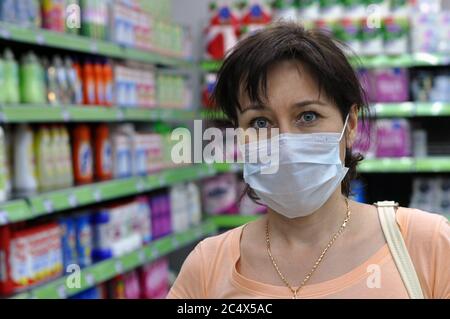 Young woman with a medical mask in a supermarket and looking at the camera. The concept of protection against coronavirus, and other respiratory Stock Photo