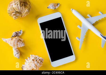 Empty screen smartphone, decorative airplane and seashells, template for app presentation. Summer travel planning. Mock up. View from above. Flat lay Stock Photo