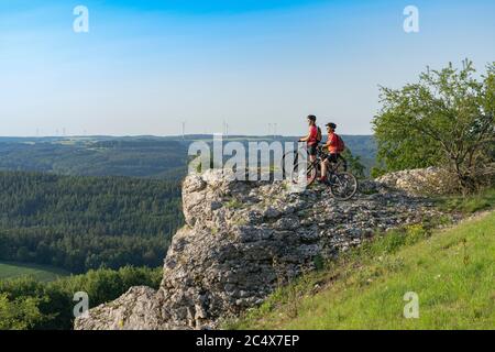 Grandmother with electric mountain bike and granddaughhter without electric help on a smooth meadow trail in the Franconian Switzerland area of Bavari Stock Photo