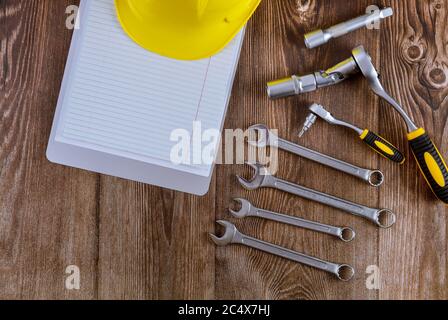 Setting spiral notepad of tools for auto mechanic, yellow safety helmet in spanner wrench automobile on wood background Stock Photo