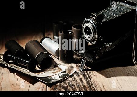 Vintage camera, photographic film and old photos on a wooden table. Stock Photo