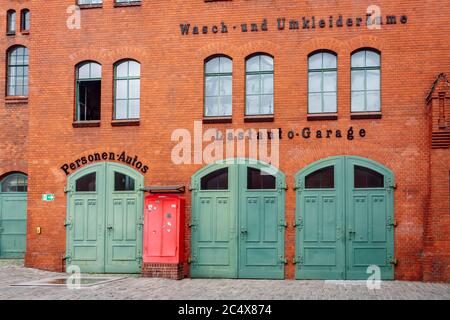 Beautiful industrial red brick facade with three vintage green garage doors. Former truck garage in the courtyard of the Kulturbrauerei Cultural Cente Stock Photo