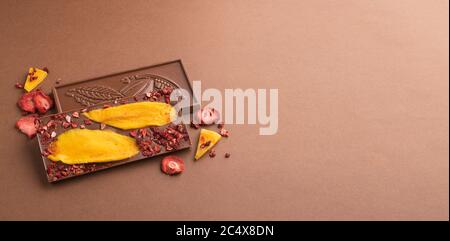 Chocolate milk Belgian bar with the addition of fruit slices of strawberry mango on a brown background. Dessert food Stock Photo