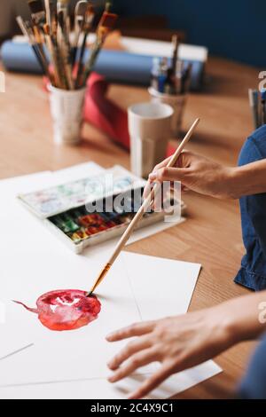 Close up painter sitting on floor drawing by colorful watercolor on paper with paint tools near at home isolated Stock Photo