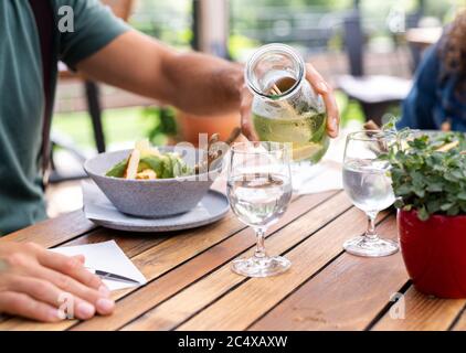 Midsection of couple sitting outdoors on terrace restaurant, having lunch. Stock Photo