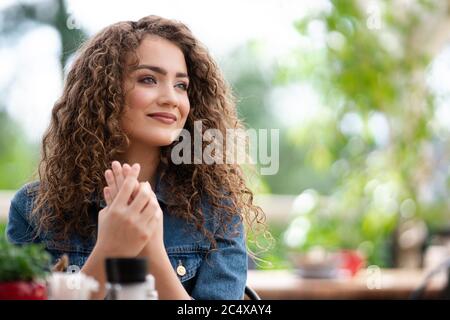 Happy young woman sitting outdoors on terrace restaurant. Copy space. Stock Photo