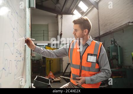 Male factory worker writing on a whiteboard at the factory Stock Photo