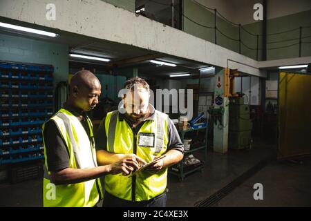 Two male factory workers discussing over a digital tablet at the factory Stock Photo