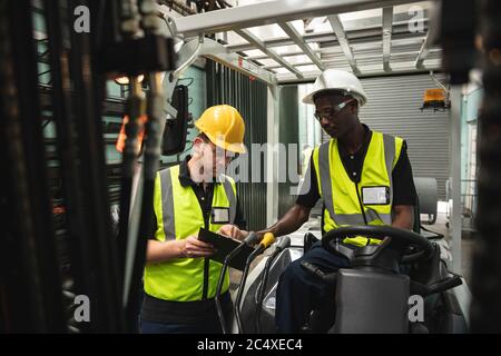 Two male factory workers discussing over a digital tablet at the factory Stock Photo