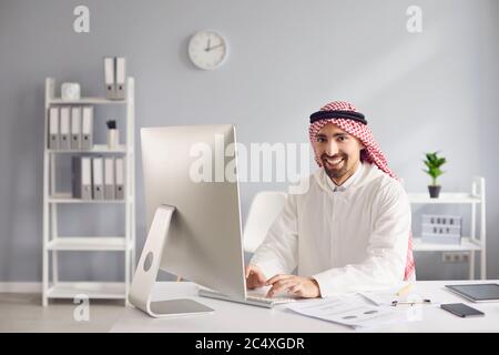 Arab man working analyzing typing at a table with a computer in the office. Stock Photo
