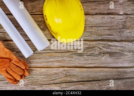 Builder of architects blueprints working on engineering office construction plans safety gloves on yellow safety helmet hard hat Stock Photo